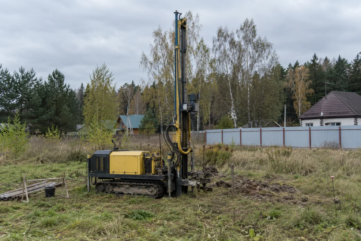 Компактная буровая установка на травяном участке рядом с деревьями