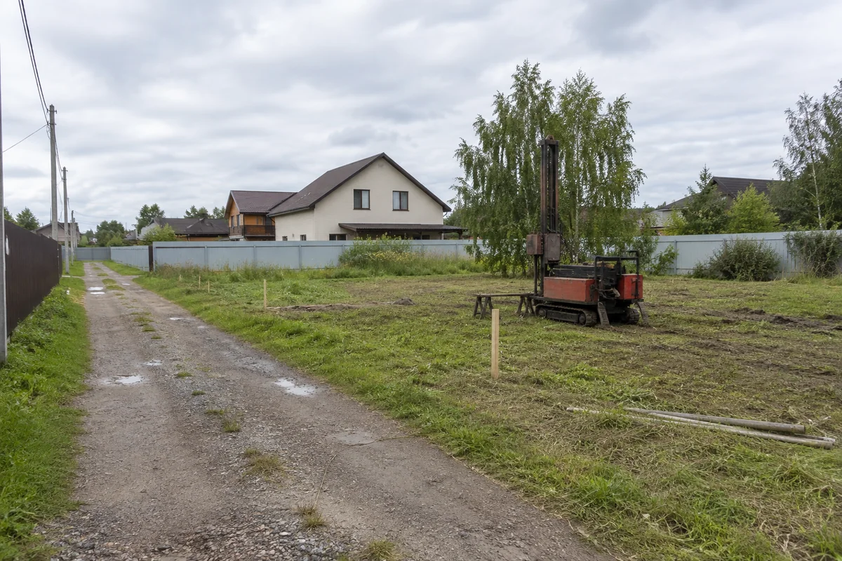 Буровая установка рядом с грунтовым проездом на участке под дом